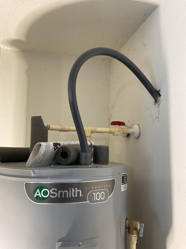 Plumber installed expansion tank to wall using metal bracket to help extend water heaters life by relieving excess pressure when the water inside heats up.