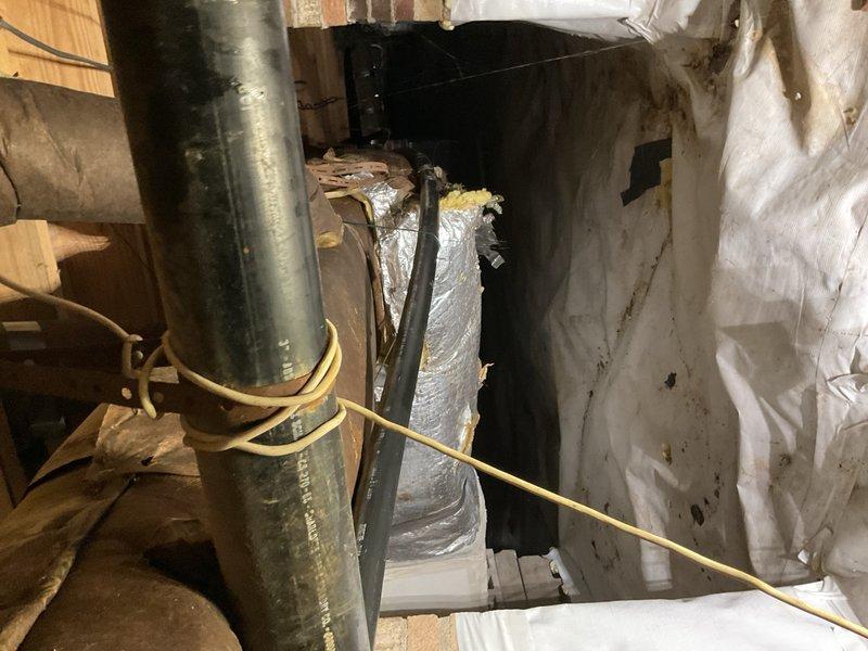 Completed inspection and documentation of drainage culvert system and HVAC infrastructure in confined utility space. Corrugated metal culvert pipe showed standing water accumulation with visible sediment deposits and corrosion at waterline, indicating potential drainage flow issues requiring monitoring. Interior HVAC space revealed aged ductwork system with compromised insulation materials, deteriorated vapor barriers exhibiting moisture staining, and accumulated debris throughout accessible areas, documenting current condition for maintenance planning and future remediation recommendations.