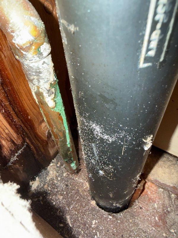# Plumbing System Access and Inspection

Created access opening in wall to expose and inspect plumbing infrastructure. Documented condition of existing drainage and water supply lines, including modern PVC drain piping and aging copper supply pipes showing corrosion and mineral deposits. Identified areas of concern with oxidized copper piping and potential deterioration requiring monitoring or future replacement.