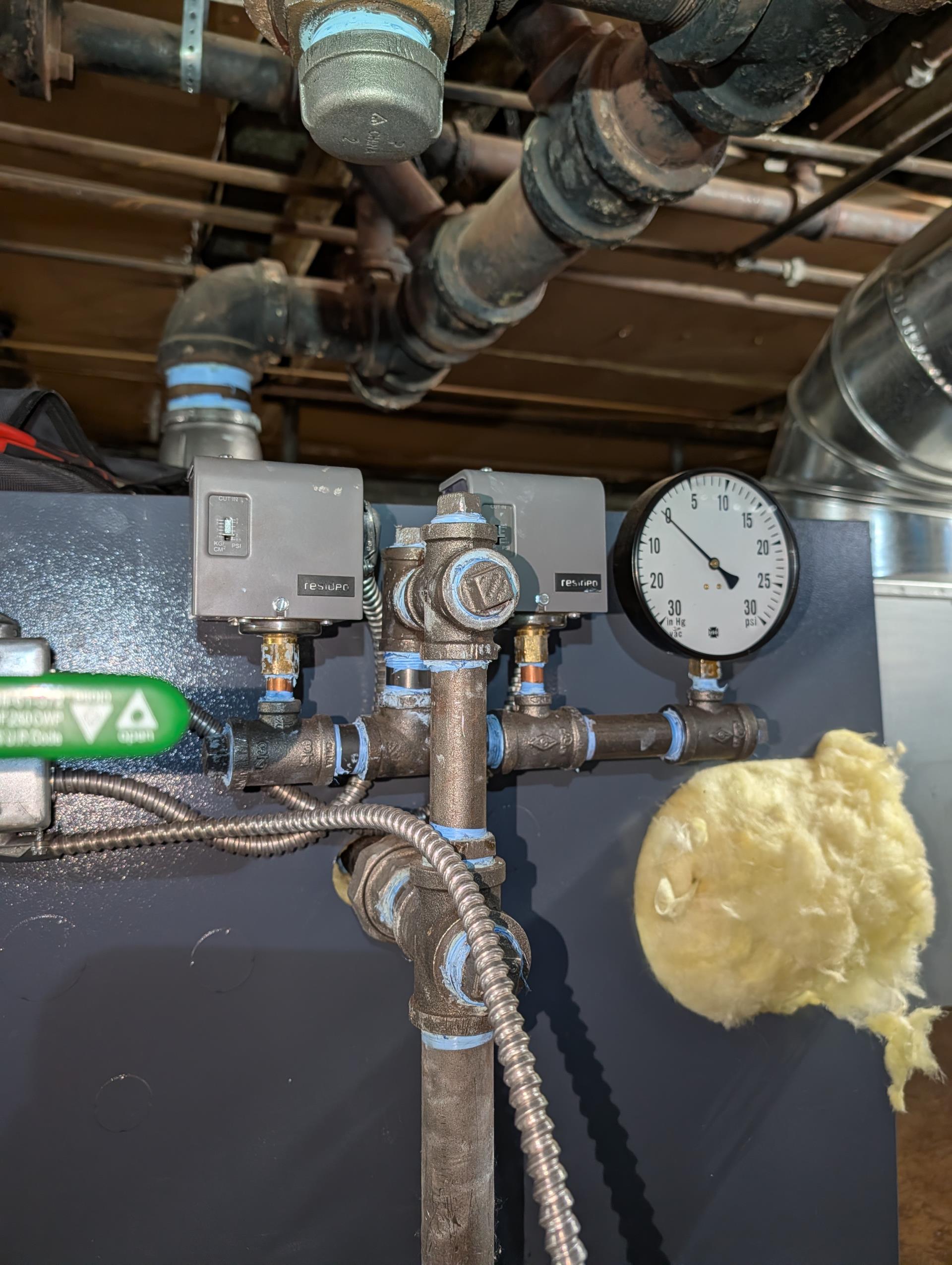 Boiler was overfilled.
Drain approx 12-15 gallons to get water level to design.
Checked over wiring,

One big issue has been thermostat location it is in a corner about 10’ up on first floor where there is a breeze from entrance way. The temperature there is 7° cooler than the temperature in any of the apartments themselves. 
We installed Honeywell S1200 Elite pro thermostat with equipment interface module and a room sensor.  
Placed the room sensor on a wall in a second floor apartment and configured new thermostat to use this sensor as the temperature input.
Set thermostat target 70°
Monitored boiler operations.
Set auto water feeder delay period to 10 min.

Tightened packing nuts on 3 problem radiator valves. They were very lose. 

There are a couple air vents that need to be replaced. We will provide estimate. 

System will run alot less often now by virtue of having temperature being read from an actual apartment. 
