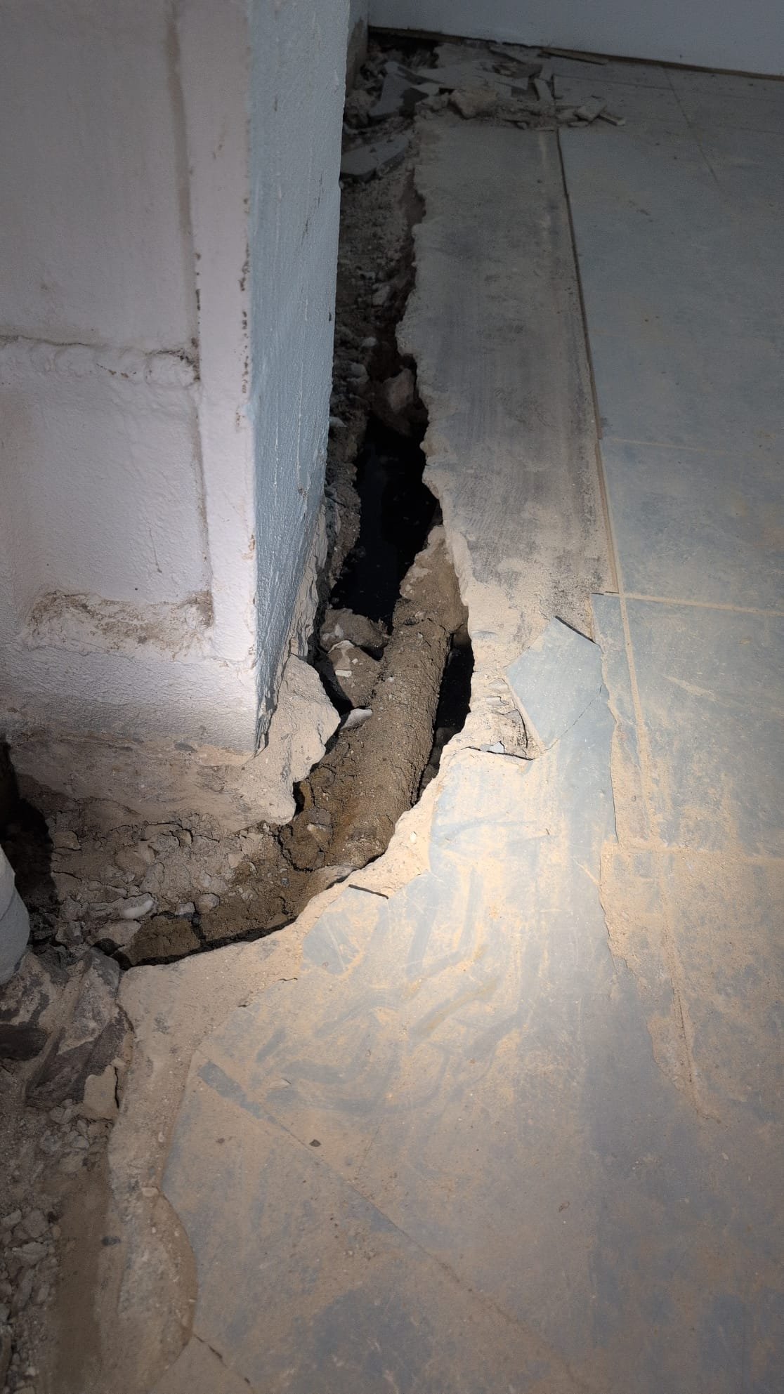 Today, we were called to address an issue in the basement. While waterproofing contractors were working, they discovered a collapsed drain line. This line connects only to the kitchen faucet and the washing machine drain. Upon inspection, I noticed a section of galvanized pipe beneath the floor. Running the water revealed movement, confirming the leak's location. To fully expose the line, we had to jackhammer slightly more. The client was informed about the possibility of further collapse further down the line. Our focus was on ensuring the line was properly exposed and assessed for any additional damage.