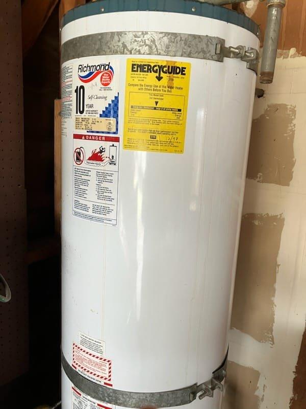 Responded to service call for residential water heater with bottom tank leak. Removed and disposed of failed unit, which had no visible tank information but was determined to be a 40 or 50 gallon gas atmospheric vent model. Installed new Richmond brand 40 gallon residential gas water heater in basement utility area. Connected water supply lines, gas line with flexible corrugated connector, and venting system through existing infrastructure. Installed temperature and pressure relief valve, tested all connections for leaks, and verified proper combustion and venting operation. Advised customer of permitting requirements and provided arrival window of 2-5 PM for installation appointment.