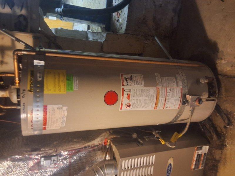 Replaced failed 1998 50-gallon gas water heater with new American Standard 50-gallon atmospheric gas water heater in basement utility room. Removed and properly disposed of old unit, installed new tank with copper supply line connections, established proper venting, and connected gas line with black flexible connector. Verified all connections for leaks, tested unit operation, and ensured compliance with local permitting requirements for residential water heater replacement.