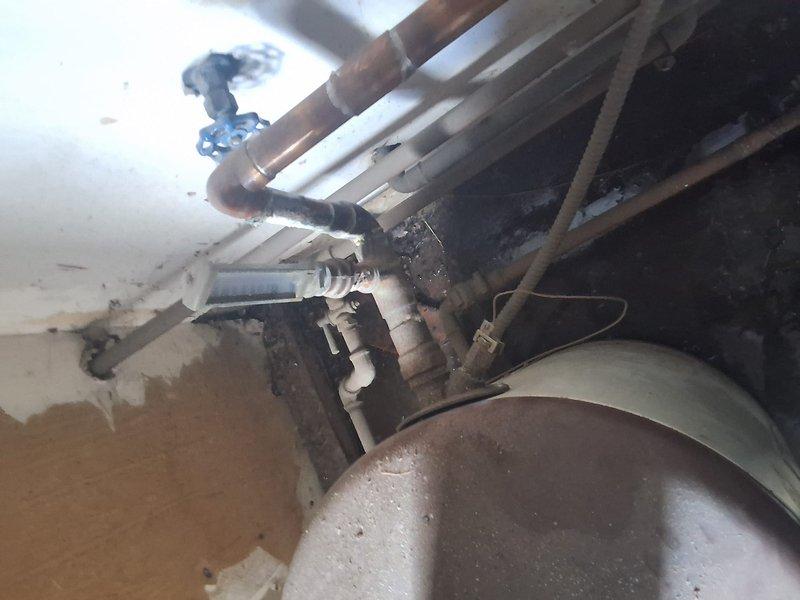 Conducted commercial site assessment for multi-unit residential property experiencing water heater system failure. Existing boiler system serving 12 individual units (one bathroom each) exhibited active leaking with visible water damage to surrounding walls and condensation on distribution piping. Documented current equipment configuration including deteriorated piping infrastructure, valve assemblies, and cylindrical storage component showing significant age-related wear. Provided estimate for complete system replacement, transitioning from boiler configuration to conventional tank-style water heating system to meet property requirements and restore hot water service to all units.