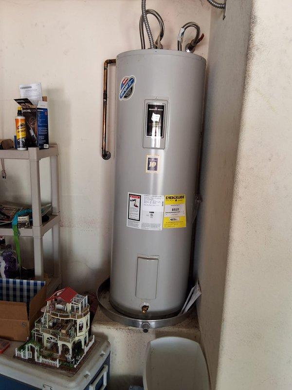 Performed preventive maintenance inspection on 12-year-old 50-gallon electric water heater located in utility area. Evaluated overall condition of unit, including copper piping connections, flexible braided supply lines, and electrical components. Discussed replacement options and provided estimate for installation of new 50-gallon electric water heater model due to age of existing unit approaching end of typical service life. Documented current installation with photographs showing tank condition, plumbing connections, and surrounding clearances. Reviewed available payment methods for future replacement work.