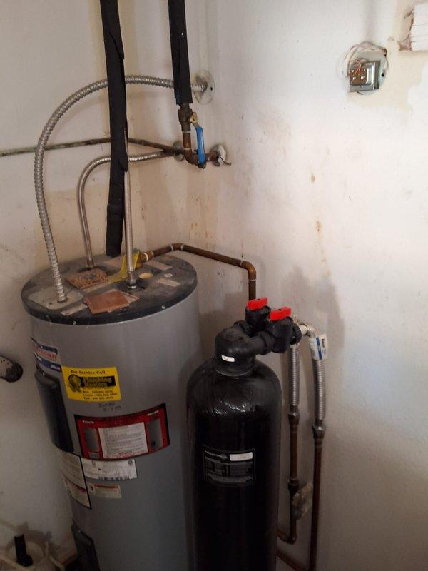 Completed preventative replacement of 13-year-old residential electric water heater with new 50-gallon RE350S6 model unit. Removed existing 4-foot tall electric water heater from utility closet, installed replacement unit with proper wall strapping, connected flexible braided supply lines, integrated with existing water treatment system, and verified all plumbing connections and electrical components for proper operation.