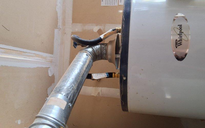 Completed residential water heater replacement with installation of 50-gallon natural gas unit in utility room. Installed additional expansion tank and drain pan for code compliance and system protection. Configured all copper piping connections with brass fittings, secured unit to wooden frame support structure, and verified proper venting through flexible aluminum duct system with appropriate wall penetrations and insulation.
