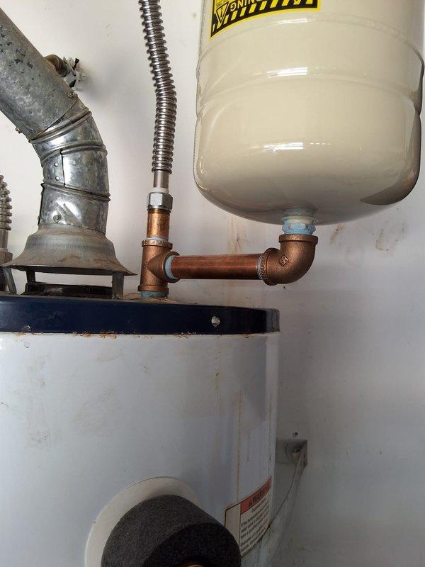 Responded to a leak at the expansion tank connection on a 2020 50-gallon gas water heater located in the garage. Upon inspection, discovered the previous installer had used galvanized fittings at the expansion tank connection point, which caused corrosion and water leakage. Diagnosed the issue and provided repair options including replacement of the galvanized fittings with proper brass fittings, as well as the option to replace the expansion tank if needed. Documented the condition with photographs showing significant rust and corrosion at the tank top and pipe connections. Scheduled follow-up appointment for repair work.