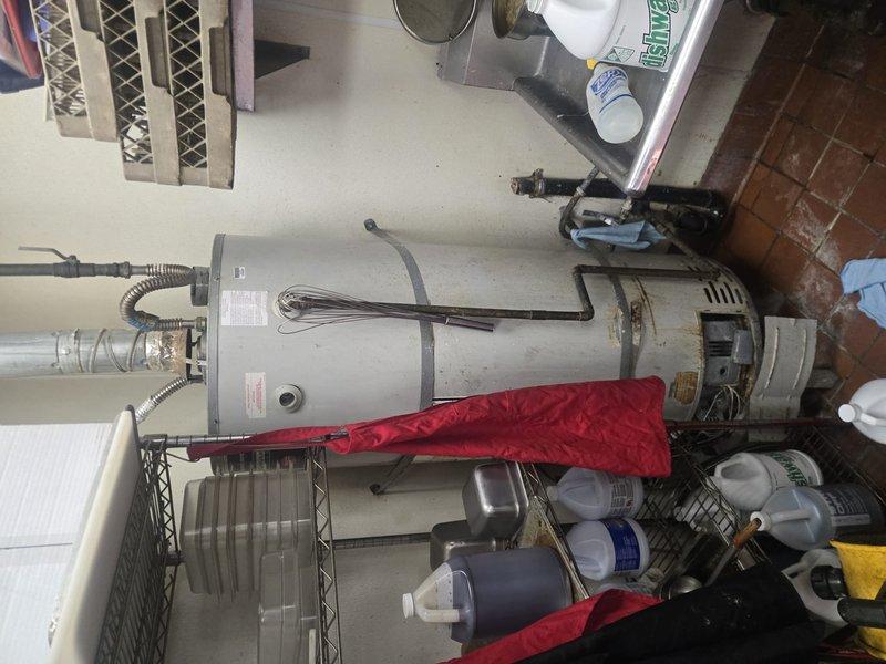 Completed comprehensive assessment of existing 40-gallon residential gas water heater and surrounding utility infrastructure for code compliance evaluation and replacement bid preparation. Documented current installation conditions including water heater positioning, venting configuration with flexible metal ducting, seismic restraint strapping, gas line connections, and clearance requirements in confined utility room space. Evaluated existing plumbing connections, temperature and pressure relief valve discharge piping, and ventilation system integration with HVAC components. Identified code deficiencies requiring correction during replacement including proper combustion air supply, adequate clearances from storage materials, updated venting standards, and seismic bracing upgrades. Photographed equipment labels, manufacturer specifications, and spatial constraints to prepare accurate material requirements and labor estimates for full water heater replacement and code remediation work.