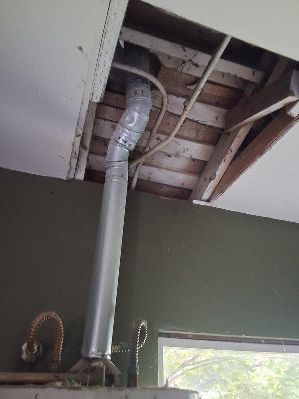 Responded to report of water heater leaking in garage. Inspected SG40T12XA01 unit and documented conditions with photos showing active installation with ceiling access point where plumbing penetrates structure and full water heater assembly with venting and gas connections. Discussed repair versus replacement options, permit requirements, and provided ballpark estimate for necessary work.