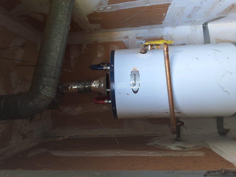 Completed on-site evaluation of water heater system at vacant property management unit. Documented existing water heater installation in utility area, including all plumbing connections, gas line with yellow shut-off valve, hot and cold water lines with blue and red flexible connections, and venting system. Photographed current condition showing copper piping, flexible metallic ducting, mounting brackets, and overall installation configuration. Assessed unit requires full replacement with permit and final inspection. Communicated findings to office for formal pricing and permitting process as per property management account protocol.