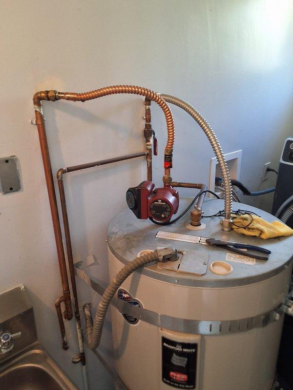 Responded to service call for leaking water heater flex line. Upon arrival, inspected 50-gallon electric Bradford White water heater model RE350S6 and identified active leak originating from flexible supply line connection above the unit. Evaluated the condition of both hot and cold water flex lines and associated copper piping connections. Documented equipment specifications and photographed the installation, including the recirculation pump system and overall plumbing configuration. Discussed repair options with property owner, including replacement of the failed flex line connection. Provided estimate for parts and labor to replace the leaking flexible connector, as well as option for complete water heater replacement if desired. Customer to advise on preferred course of action to resolve the leak issue.