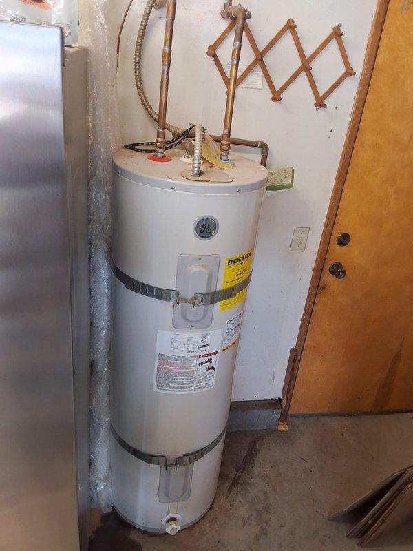 Replaced failed 50-gallon electric water heater (Model PE50T09AAH, Serial GEM481302185) due to oil leak. Installed new American Standard residential electric water heater with proper seismic strapping, connected copper supply lines and flexible hoses to top connections, and verified all plumbing connections for proper operation. Unit secured to wall with two metal restraint straps per code requirements and tested for functionality.