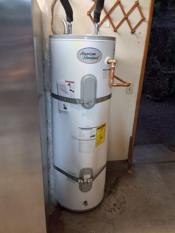 Replaced failed 50-gallon electric water heater (Model PE50T09AAH, Serial GEM481302185) due to oil leak. Installed new American Standard residential electric water heater with proper seismic strapping, connected copper supply lines and flexible hoses to top connections, and verified all plumbing connections for proper operation. Unit secured to wall with two metal restraint straps per code requirements and tested for functionality.