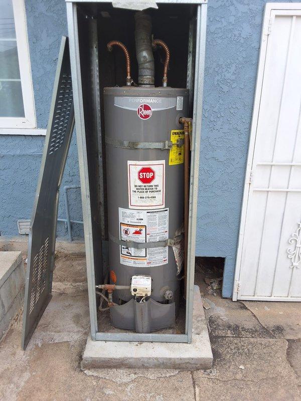 Performed inspection on a 7-year-old Rheem Performance 40-gallon gas water heater experiencing active leaking. Assessed unit condition, documented installation with photographs showing exterior cabinet enclosure, plumbing connections, copper flex lines, and vent piping. Provided estimate for replacement with new 40-gallon gas water heater, discussed permit requirements, and reviewed available payment options with property owner.
