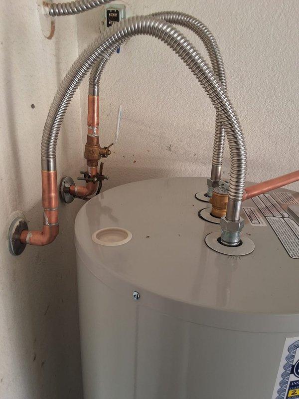 Responded to a leaking water heater and performed a complete residential unit replacement. Removed the failed 50-gallon Bradford White electric water heater and installed a new Bradford White 50-gallon electric model M250S6DS-INCMW (S#JA160684146). Connected copper supply lines with brass fittings, installed temperature and pressure relief valve, and completed electrical connections using flexible metallic conduit from the existing junction box to the unit per code requirements.