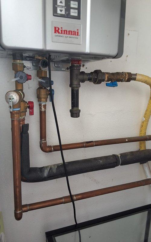 Performed preventive maintenance inspection on a 5-year-old Rinnai tankless water heater system. Evaluated unit condition, plumbing connections including copper piping with isolation valves and pressure gauge, flexible gas line with shutoff valve, and exhaust venting system. Confirmed unit is under warranty coverage, discussed permit requirements for future replacement work, and provided estimate for 50-gallon gas water heater installation with available payment options.