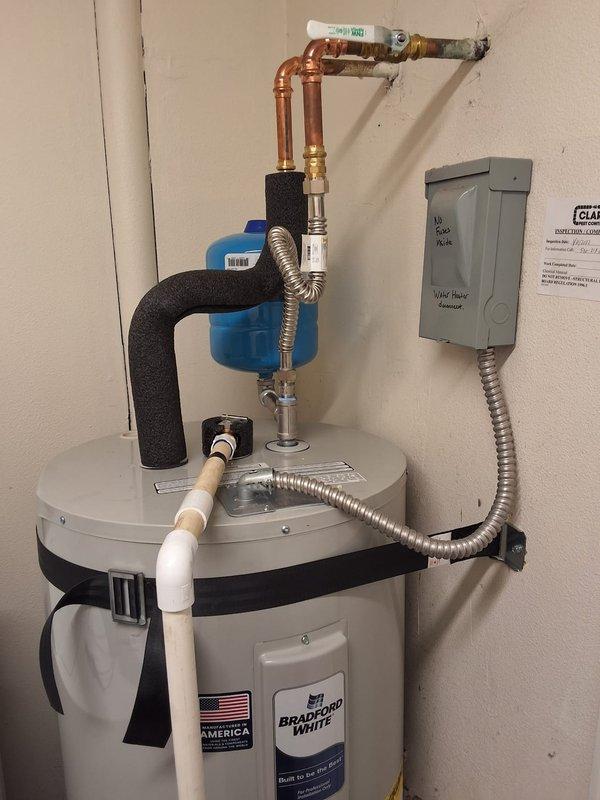 Responded to property management complaint regarding inadequate hot water duration (2-3 minutes only) at rental unit. Performed diagnostic evaluation on Bradford White 50-gallon electric water heater that had previously been serviced by another plumber who replaced the unit under warranty without resolving the issue. Conducted thorough inspection of water heater installation, electrical connections, plumbing configuration, and associated components including water softener system. Examined copper supply lines, PVC drain piping, pressure relief valve, electrical panel connections, and insulated piping. Documented existing installation with photographs showing complete system layout including wall-mounted electrical box, flexible conduit connections, brass fittings, and valve assemblies. Evaluated potential causes including undersized unit for demand, electrical supply issues, thermostat malfunction, sediment buildup, mixing valve problems, or improper installation. Contacted office with