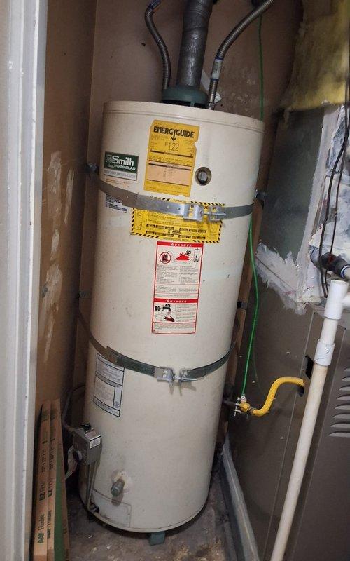 Performed inspection of aging gas water heater showing signs of wear and discoloration. Unit age and serial number unavailable due to label deterioration. Evaluated existing installation including gas line connections, plumbing fittings, and grounding wire configuration. Observed yellow flexible gas line, brass valve assembly, and metallic flexible connectors at top of unit. Discussed replacement options with customer for 40 or 50-gallon gas water heater. Provided ballpark estimate range for complete replacement installation. Reviewed permit requirements for water heater replacement work. Documented existing conditions through photographs showing current unit placement in utility closet, visible wear patterns, and connection points. Advised customer of available payment methods and next steps for proceeding with replacement.