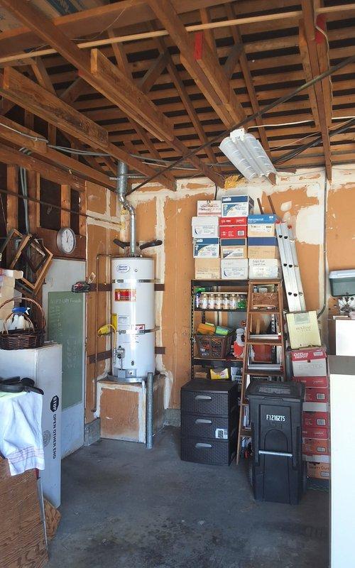 Completed replacement of 50-gallon gas water heater located in residential garage. Removed existing failed unit and installed new 50-gallon gas water heater on wooden platform with proper venting and gas line connections using flexible yellow gas connector. Connected all supply and discharge piping, installed temperature and pressure relief valve with appropriate discharge piping, and verified all connections for proper operation and safety compliance. Customer advised of permit requirements for installation.
