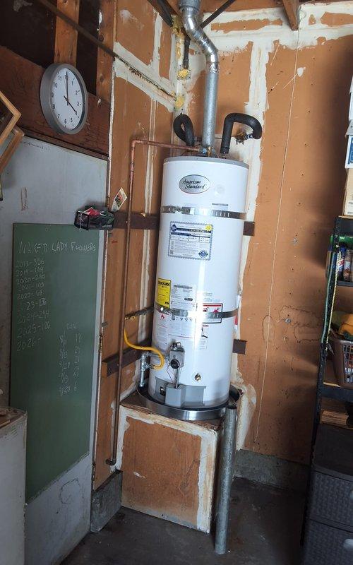 Completed replacement of 50-gallon gas water heater located in residential garage. Removed existing failed unit and installed new 50-gallon gas water heater on wooden platform with proper venting and gas line connections using flexible yellow gas connector. Connected all supply and discharge piping, installed temperature and pressure relief valve with appropriate discharge piping, and verified all connections for proper operation and safety compliance. Customer advised of permit requirements for installation.