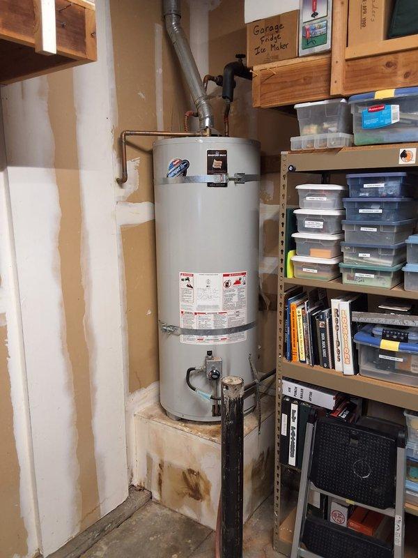 Responded to a leaking water heater emergency and found a 25-year-old Kenmore unit that had reached end of service life. Removed the failed water heater and installed a new American Standard 40-gallon gas water heater on the existing platform in the utility area. Connected copper supply lines, installed new gas control valve assembly with flexible gas line connector, verified all connections for leaks, attached black exhaust vent piping, and tested unit operation. Advised customer that permitting would be added to estimate as required by local code. Arrival window of 12-3 PM was maintained.