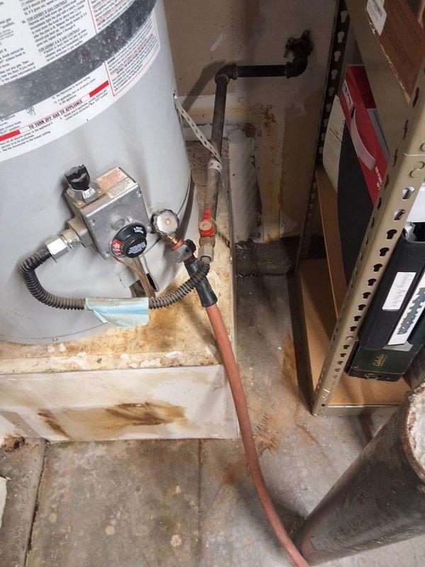 Responded to a leaking water heater emergency and found a 25-year-old Kenmore unit that had reached end of service life. Removed the failed water heater and installed a new American Standard 40-gallon gas water heater on the existing platform in the utility area. Connected copper supply lines, installed new gas control valve assembly with flexible gas line connector, verified all connections for leaks, attached black exhaust vent piping, and tested unit operation. Advised customer that permitting would be added to estimate as required by local code. Arrival window of 12-3 PM was maintained.