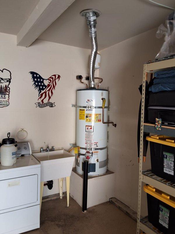 Replaced failed 2004 50-gallon gas water heater (Serial: RULN1004V05657) in garage/utility room with new unit on existing platform. Removed old water heater, installed new unit with proper venting through ceiling, connected copper water supply lines, yellow flexible gas line with shutoff valve, temperature and pressure relief valve with discharge piping, and verified all connections for proper operation and code compliance.