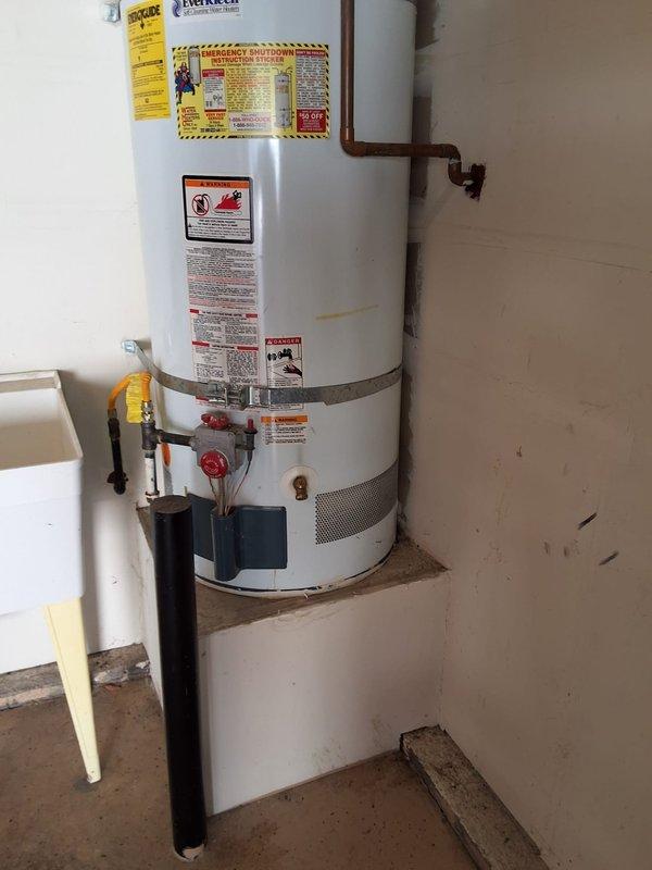 Replaced failed 2004 50-gallon gas water heater (Serial: RULN1004V05657) in garage/utility room with new unit on existing platform. Removed old water heater, installed new unit with proper venting through ceiling, connected copper water supply lines, yellow flexible gas line with shutoff valve, temperature and pressure relief valve with discharge piping, and verified all connections for proper operation and code compliance.