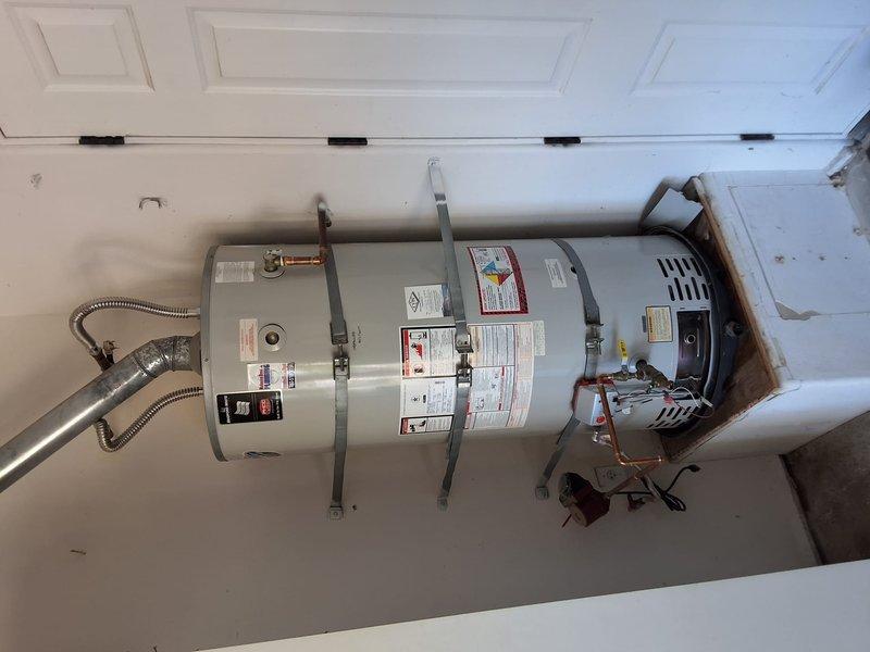 Completed full replacement of 75-gallon residential gas water heater in garage utility area. Removed existing unit and installed new 75-gallon gas water heater with all required connections including copper water supply lines, gas line connections, temperature and pressure relief valve, and proper venting system. Secured unit with metal strapping per code requirements, connected electrical components, and verified all plumbing connections for proper operation and leak-free performance.