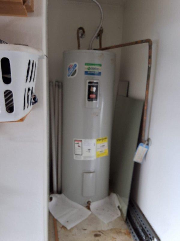 Completed inspection of 50-gallon electric water heater showing visible signs of age including rust staining at base and top connections. Provided estimate for water heater replacement, discussed permit requirements, available payment options, and documented existing installation with photographs showing current plumbing connections and utility closet configuration.