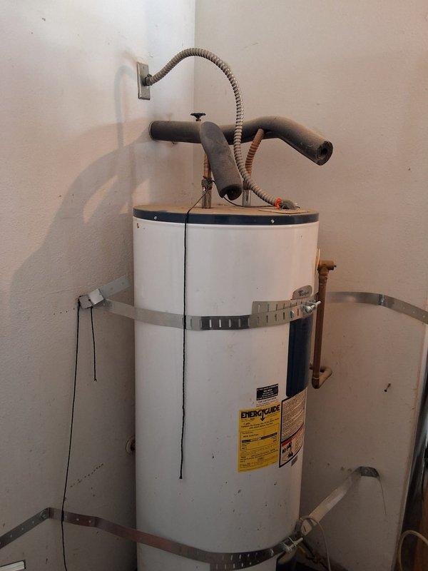 Performed inspection on leaking Whirlpool water heater (Model: E2F65HD0452, Serial: 0826332) located in utility room. Documented unit condition with photographs showing visible wear on exterior casing, existing plumbing connections including copper supply lines, PVC discharge piping, and flexible connector at top of unit. Discussed permit requirements with property owner and explained available payment options for future replacement or repair work.