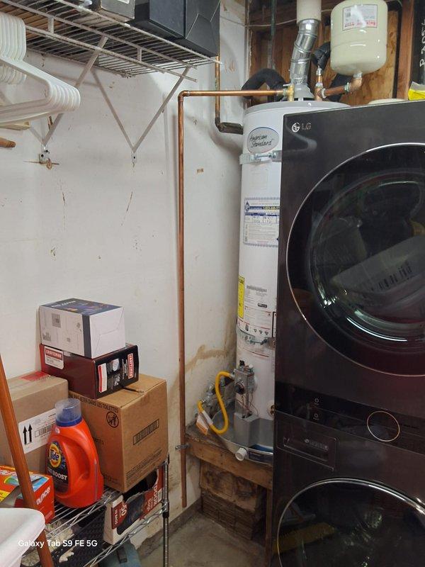 Completed no-charge warranty service on gas water heater model GN40T1-3-6, serial M25-062300, within first year of installation. Inspected unit installation, verified proper gas line connections, plumbing connections, and operational status. Documented equipment condition with photos showing water heater properly positioned on pallet base with copper piping, yellow flexible gas line, brass drain valve, and all manufacturer labels intact in utility room setting alongside stacked washer/dryer unit.