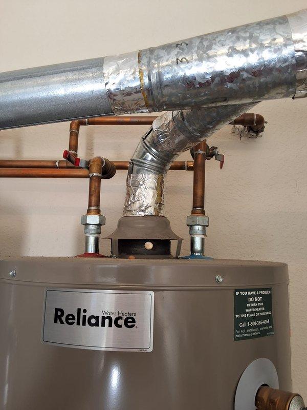 Responded to service call for Reliance water heater experiencing loud popping noises and sparking. Inspected approximately 8-year-old unit with unavailable model and serial number information. Upon examination, observed significant condensation and frost buildup on galvanized ductwork and copper supply piping above water heater, indicating potential temperature differential issues. Documented plumbing configuration including compression fittings, dielectric unions, and red-handled isolation valves on hot and cold water lines. Photographed heavily soiled air filter with substantial dust, debris, and particulate accumulation requiring replacement. Noted electrical wiring connections at filter mounting bracket. Advised customer that permit requirements need to be determined prior to any repair or replacement work. Provided general ballpark estimate range for potential water heater replacement and associated plumbing modifications. Scheduled follow-up appointment window for further action 
