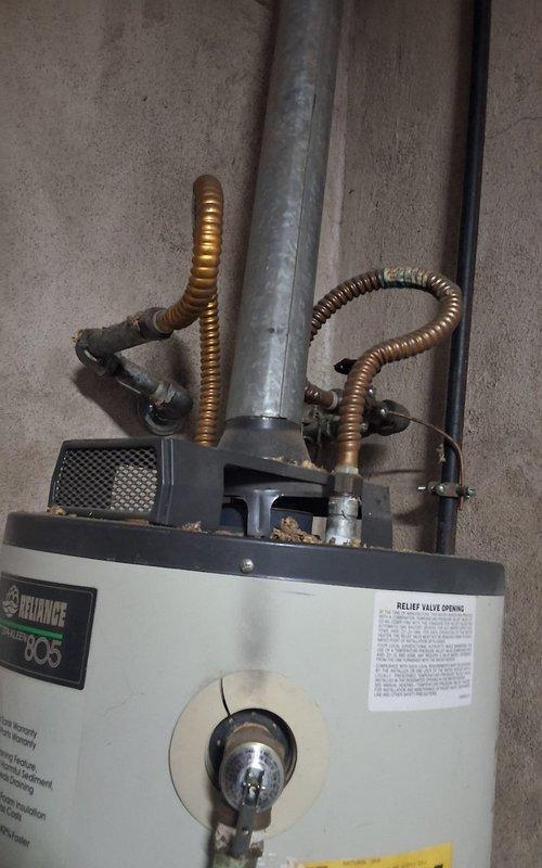 Responded to service call for leaking water heater. Upon inspection, identified active leak originating from bottom of 10+ year old 50-gallon gas water heater unit. Observed deteriorated wooden platform beneath unit with visible water damage and staining on concrete floor, confirming chronic leakage. Documented existing installation including copper supply lines, flexible connectors at top of unit, seismic restraint strap, and gas valve assembly. Evaluated overall condition of Reliance brand water heater and determined unit has exceeded serviceable lifespan. Photographed installation and leak evidence for documentation purposes. Provided customer with replacement options for 50-gallon gas water heater and discussed estimated costs for complete changeout. Advised customer of available arrival window for installation scheduling.