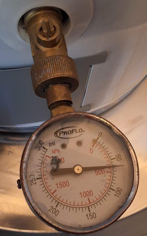 Responded to warranty service call for 40-gallon natural gas automatic storage water heater, Model GN40T1-3-6, Serial B25-007708. Performed diagnostic inspection of unit to identify reported issue and verify warranty coverage eligibility. Inspected water heater tank exterior condition, verified all manufacturer specification labels and safety documentation intact and legible. Evaluated system pressure using gauge measurement to confirm proper operating parameters within acceptable range. Documented equipment condition through photographs showing tank specifications, AHRI certification, and pressure monitoring equipment. Completed warranty inspection and verified unit operational status.