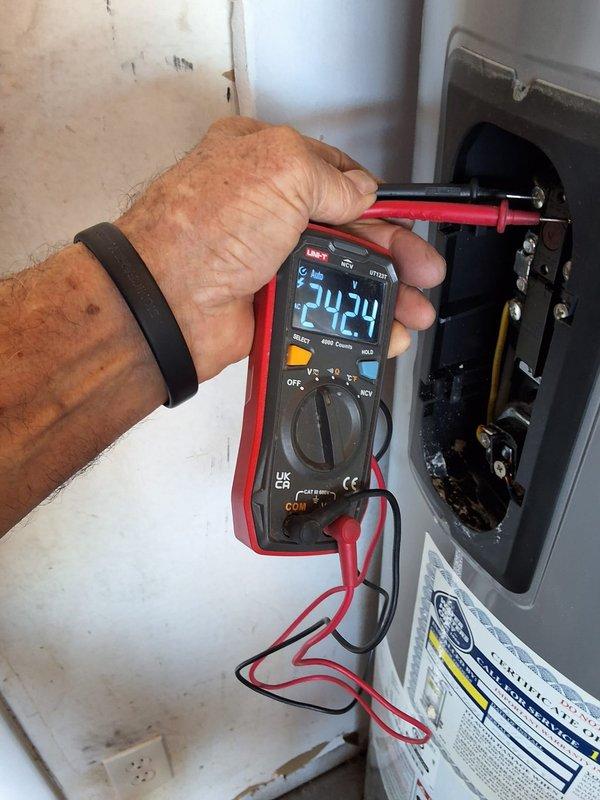 Responded to warranty service call for Rheem 50-gallon electric water heater model PROE05T2RH95 reporting water leakage at base of unit. Performed diagnostic testing using digital multimeter to check electrical components and verify proper voltage readings of 24.24V at control panel. Conducted pressure testing with gauge to assess tank integrity and identify source of leak. Upon inspection, confirmed active water leakage originating from lower section of tank near heating element area. Verified unit is covered under active 10-year manufacturer warranty with documentation on file. Documented findings with photos showing electrical diagnostics and pressure testing equipment. Recommended tank replacement under warranty coverage due to compromised tank integrity and active leak condition that cannot be repaired.
