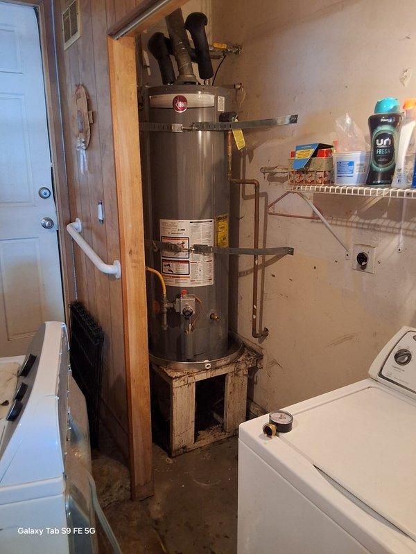 Replaced a leaking 40-gallon propane water heater (PROG40-32P) that was experiencing failure from the top of the tank. Installed new Rheem 40-gallon LP gas water heater (model LGSN40T1-3-6LP) with expansion tank, new venting system including vertical black exhaust pipe, copper supply line connections, and flexible braided hose connections. Unit was positioned in basement utility area and all plumbing connections were completed to code specifications, with county permit requirements advised for final approval.