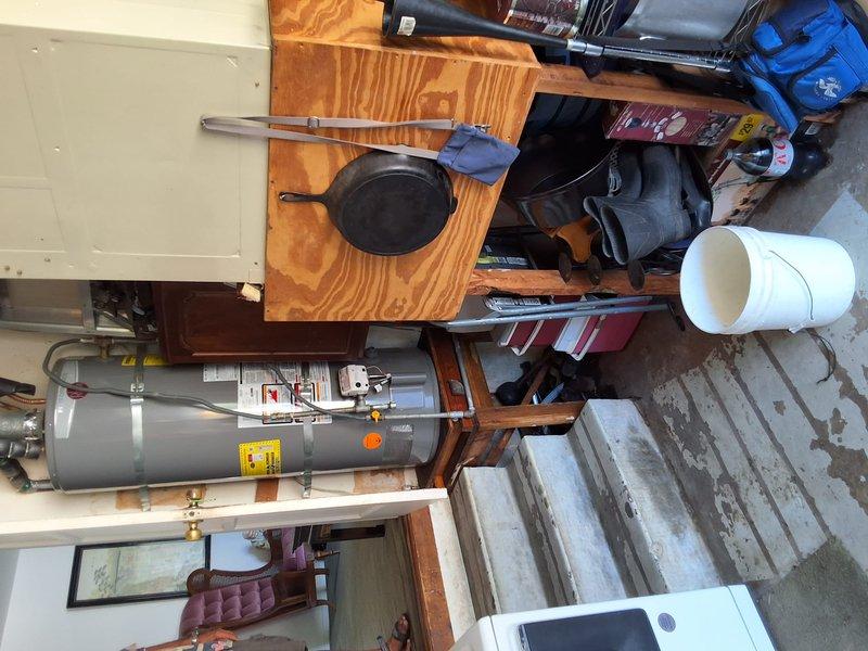 Responded to service call for leaking water heater. Upon inspection, identified unit as a 50-gallon gas water heater (Model: XG50T06HE40U0, Serial: M501409571) installed horizontally on wooden platform in basement utility area. Evaluated condition of unit, connections, and surrounding plumbing. Documented existing installation with photographs showing water heater, gas line connections with yellow fittings, flexible connector hose, control valve assembly, and supply line configuration. Discussed replacement options and permit requirements with property owner. Provided rough estimate for replacement work and reviewed available payment options. Scheduled appointment window established for future service.