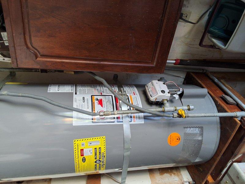Responded to service call for leaking water heater. Upon inspection, identified unit as a 50-gallon gas water heater (Model: XG50T06HE40U0, Serial: M501409571) installed horizontally on wooden platform in basement utility area. Evaluated condition of unit, connections, and surrounding plumbing. Documented existing installation with photographs showing water heater, gas line connections with yellow fittings, flexible connector hose, control valve assembly, and supply line configuration. Discussed replacement options and permit requirements with property owner. Provided rough estimate for replacement work and reviewed available payment options. Scheduled appointment window established for future service.