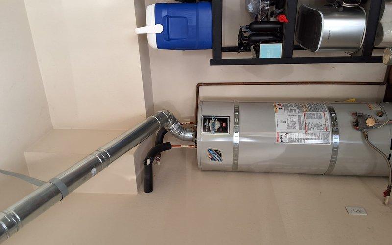 Responded to a bottom-leaking 50-gallon gas water heater and replaced it with a new 50-gallon gas unit, including a permit for the installation. The failed tank was drained, disconnected from the water, gas, and flue connections, and removed. The new heater was set on its platform, then reconnected to the copper supply lines, gas control valve, and vent piping, and secured per code.