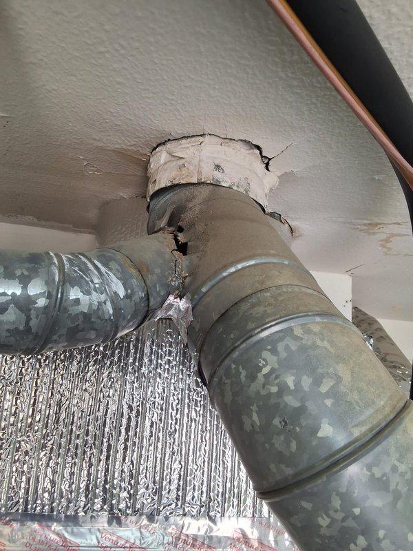 Replaced a 30-year-old, underperforming 50-gallon short gas water heater located in the garage with a new 50-gallon short gas unit, including removal and disposal of the old tank, reconnection of water supply, gas, and venting, and verification of proper ignition, operation, and leak-free connections. During the work, damaged galvanized ductwork was observed with a split at the duct junction, failed foil tape, and cracked, deteriorating mastic at the ceiling collar, and the affected area was documented and measured for a single-section sheet metal repair.