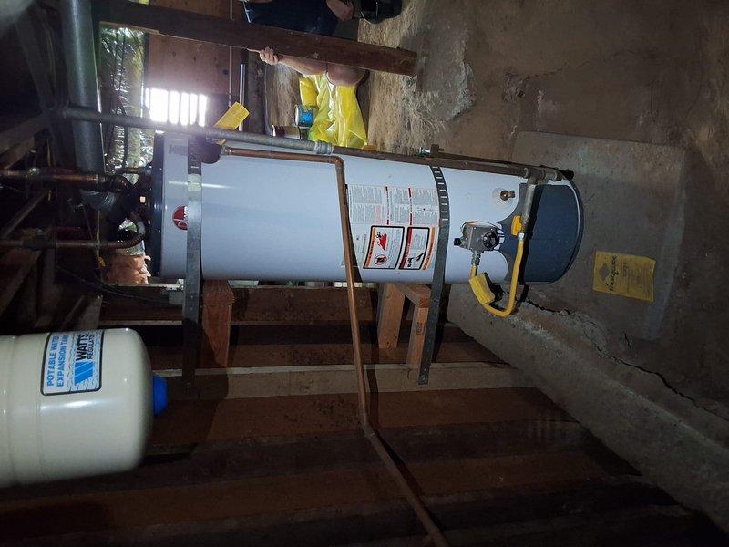 Inspected existing 40-gallon gas water heater in crawlspace installation, noting seismic strapping, flexible gas connector, copper supply piping, thermal expansion tank, and a cracked concrete pad beneath the unit. Provided replacement options for standard tank, tankless, and heat pump water heaters, and discussed permit requirements and payment options with the homeowner.