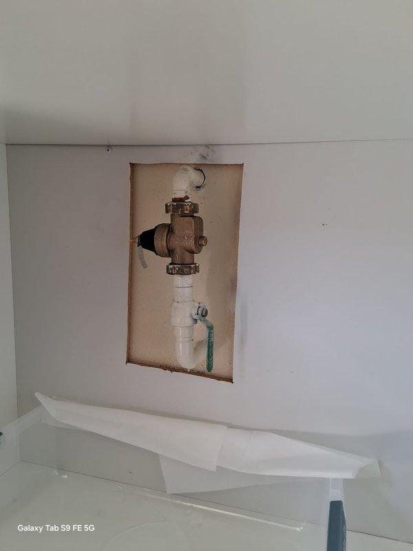 Responded to a warranty call for a leak at the shut-off ball valve on the water conditioning unit's plumbing assembly. Accessed the plumbing through the wall cutout, inspected the ball valve and connecting PVC fittings, and corrected the leak at the valve connection. Verified the assembly was dry and holding pressure with no further leaks.