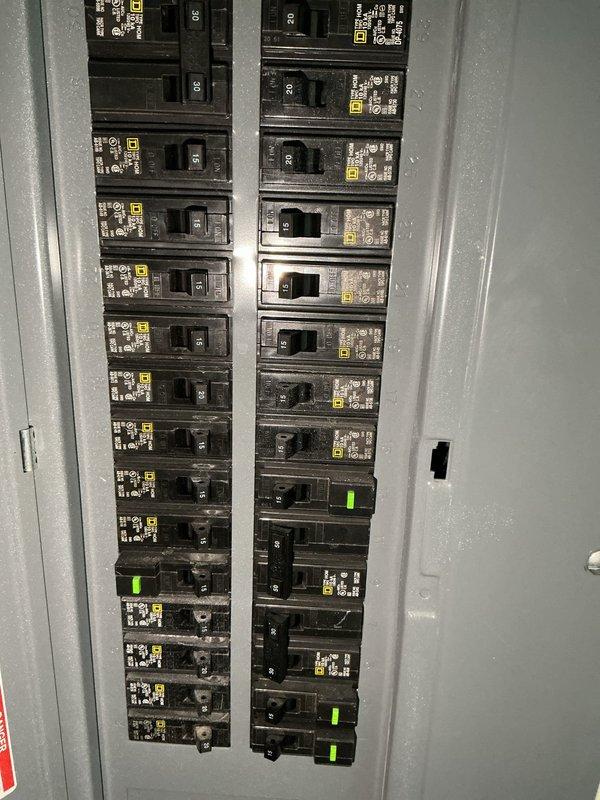 Returned to site to collect additional data for estimate and load calculation. Documented electrical panel configuration, noting multiple 20-amp breakers with QO markings and breaker positions. Also photographed plumbing and HVAC systems in utility area, including PVC drainage pipes, P-trap configuration, and furnace placement for comprehensive assessment.