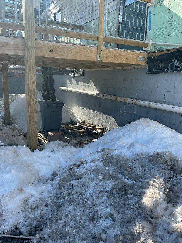 Responded to water leak service request for courtroom bathroom with frozen and broken drain lines. Conducted comprehensive inspection, documenting conditions in utility storage area and exterior foundation where PVC drain line was visible. Identified freeze damage at exterior wall penetration requiring repair of affected drain piping sections.