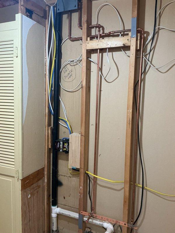 Completed bathroom renovation including demolition of cast iron tub, disconnection of water lines for tub and lavatory, and removal of toilet. Installed new 5' fiberglass shower unit with proper rough-in plumbing, requiring modification of existing copper supply lines and PVC drain connections as documented in photos of framing work.