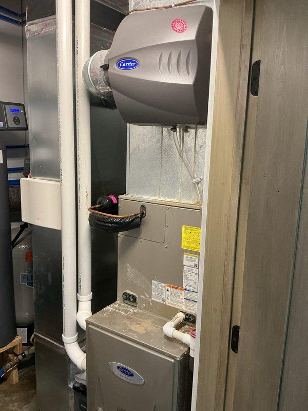 Replaced corroded humidifier water panel and installed new drain hose on Carrier humidifier system. Verified proper humidifier operation when main water supply is off and assessed need for pre-filter on supply line. Applied company identification sticker to furnace unit for new homeowner reference.