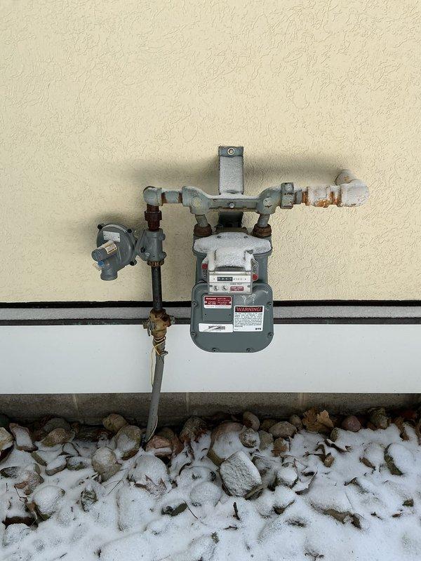 Inspected unit heater and identified a crack in the heat exchanger at the transition point to the exhaust hood. System was immediately shut down and gas supply terminated due to safety hazard from potential carbon monoxide leakage into supply air. Documented condition with photos of the ventilation fixture and gas meter assembly.