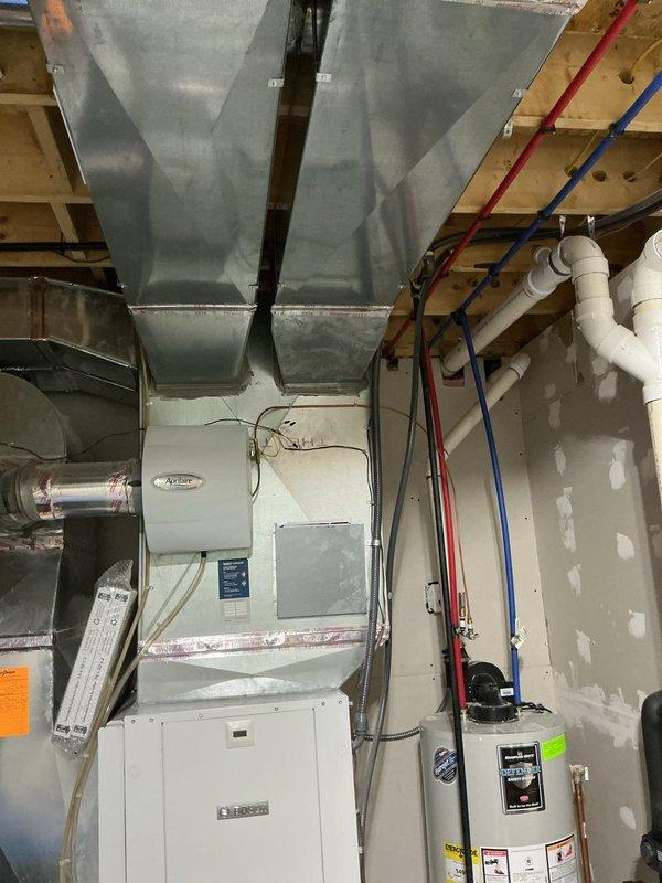 Provided estimate for adding zones to existing geothermal HVAC system. Assessed current basement mechanical setup including white air handler unit, geothermal manifold assembly with dual control valves, galvanized metal ductwork throughout exposed ceiling joists, and associated PEX plumbing connections. Documented existing system configuration with photographs to determine zoning requirements and integration points for additional zone controls with the current geo system infrastructure.